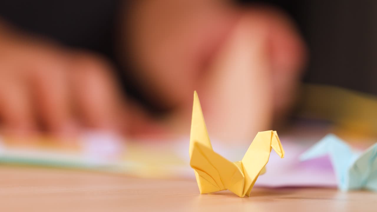 Mani piegano un foglio trasformandolo in uccelli origami su un tavolo di legno con illuminazione interna soffusa