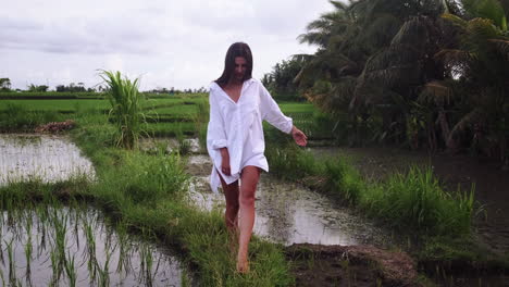 woman in a white shirt walking through a rice paddy