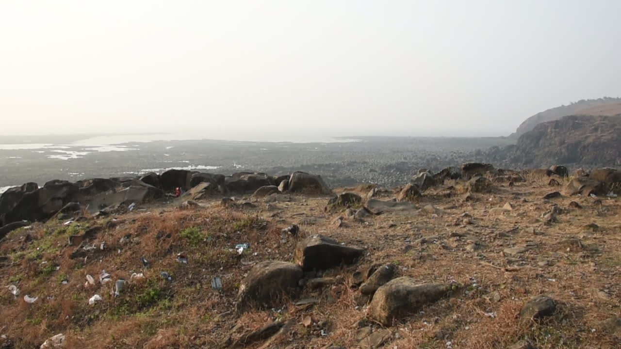 Un giovane ragazzo indiano che fa jogging ed escursioni su una scogliera di una piccola montagna vicino a una spiaggia a Mumbai, India, sfondo video in Pro res.