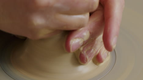 empty potters wheel, potter throwing clay onto the wheel and starting the process