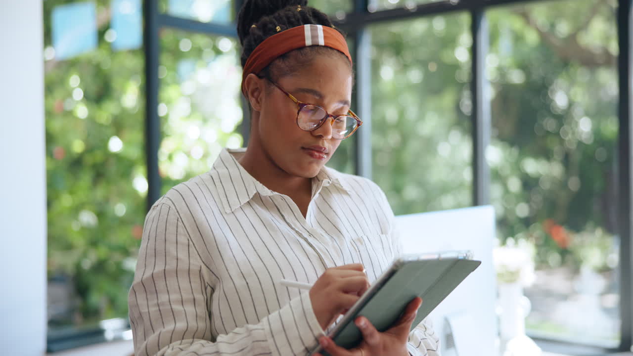 Focused Young Woman Using Digital Tablet with Stylus in Office