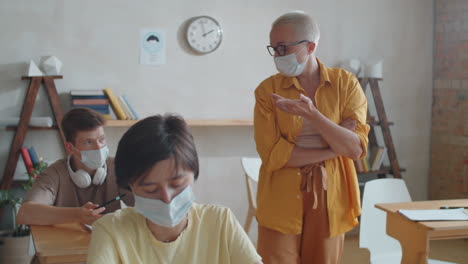 teacher and students in masks having lesson during covid-19 pandemic