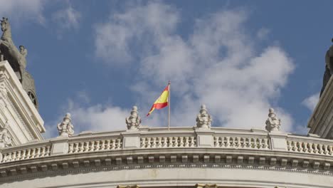 slow motion zoom out shot of a spanish flag waving at a building in madrid