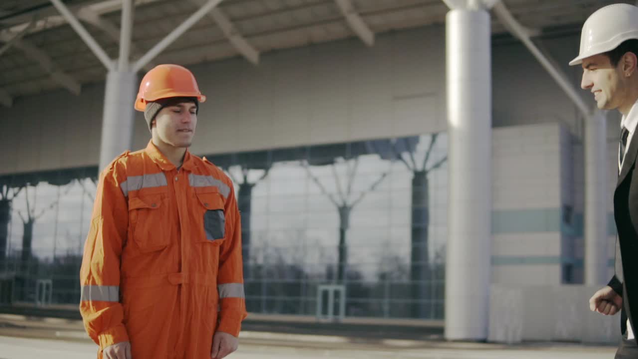Man In A Suit Giving To The Construction Worker In Uniform An Envelope With Money Bribe 1