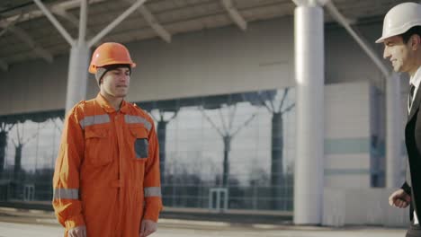 hombre de traje que le da al trabajador de la construcción en uniforme un sobre con soborno de dinero 1