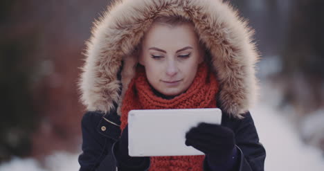 mujer positiva usando tableta digital en invierno al aire libre 2