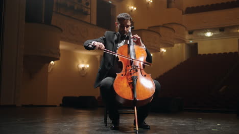 cellist is playing violoncello on scene in empty old opera house rehearsal of symphonic orchestra