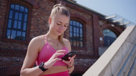 young caucasian woman in sportswear uses phone and smartwatch, closeup