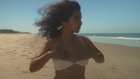 the wide view shows a close-up of a beautiful and fit woman applying sunscreen to her neck, taking care of her skin with ocean in background