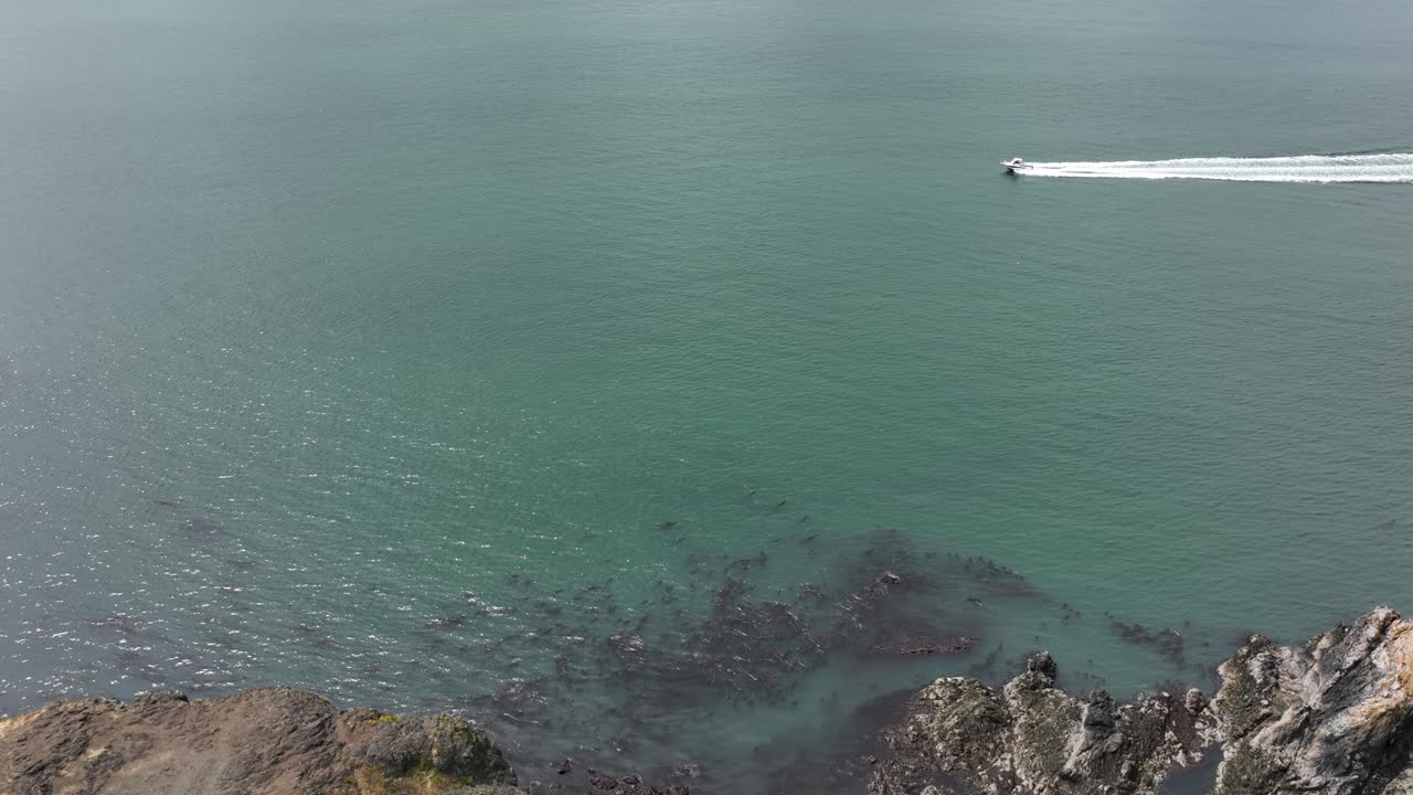 바위가 많은 해안선을 따라 빠르게 이동하는 모터보트의 조감도