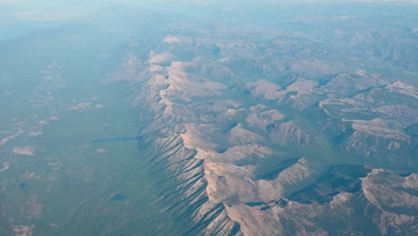 aerial drone view of rugged desert mountains and shadowed ridges at golden hour