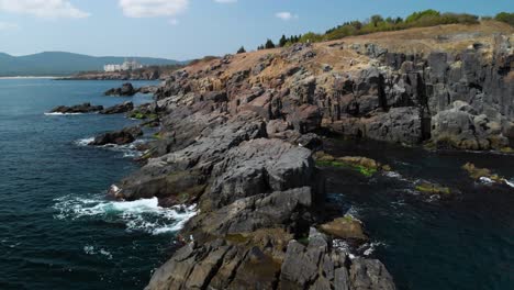 pn aéreo disparado alrededor de grandes rocas en el mar junto a la orilla en un día soleado de verano