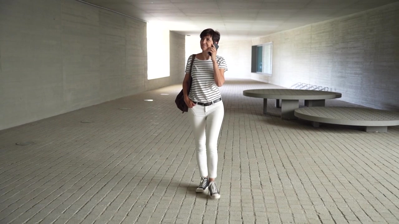 Una donna elegante passeggia in un ambiente architettonico contemporaneo e moderno.