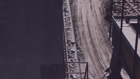 conveyor belt transports crushed stones alongside a dirt road in a quarry