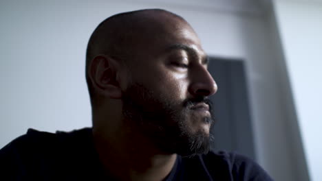 bald ethnic minority male looking out sideways pensively thinning