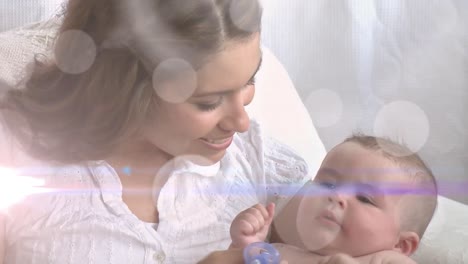 animation of glowing spots over happy caucasian mother with baby