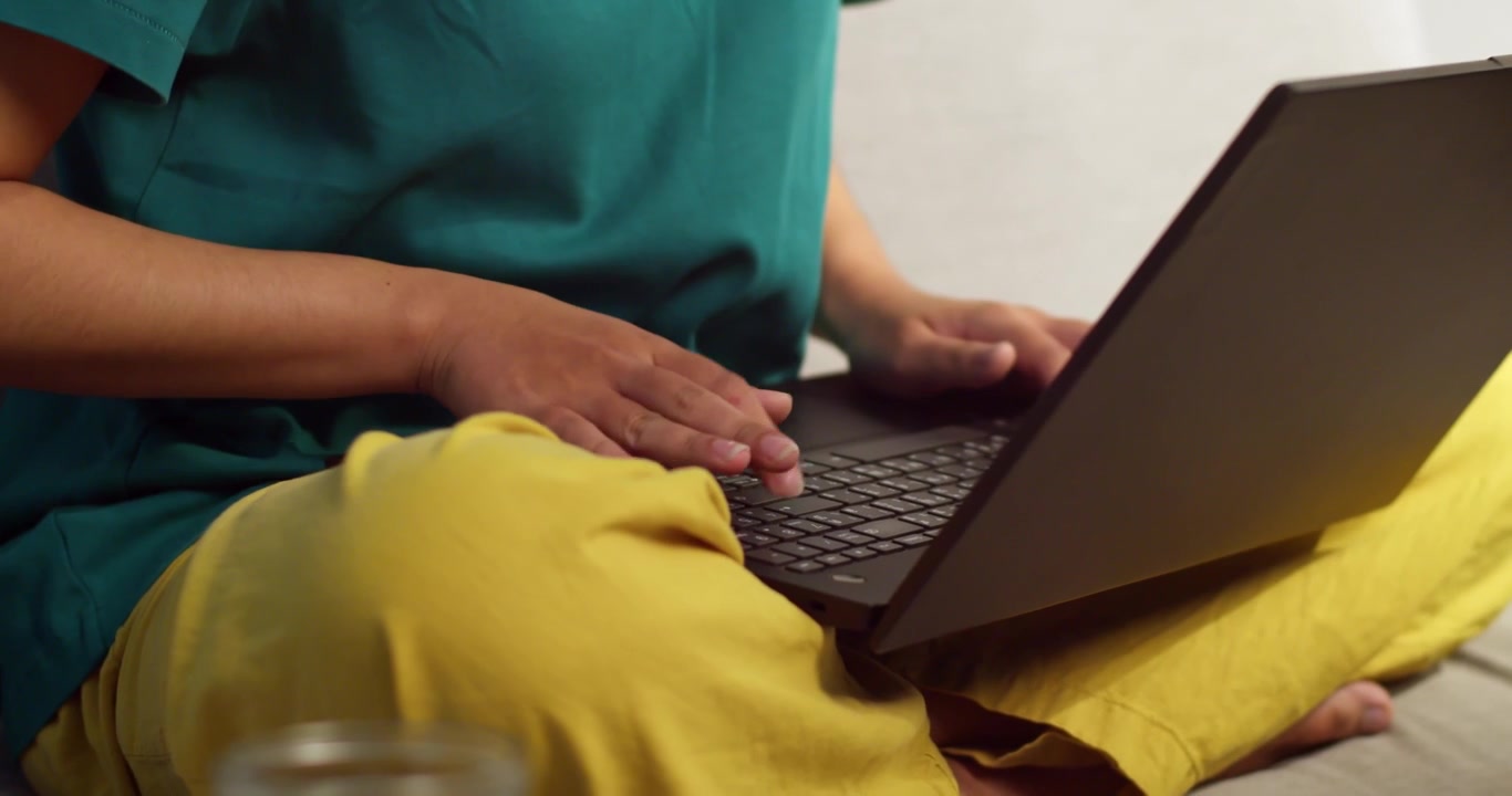 En fokuseret person arbejder på sin bærbare computer i et hyggeligt hjemmemiljø, der viser produktivitet