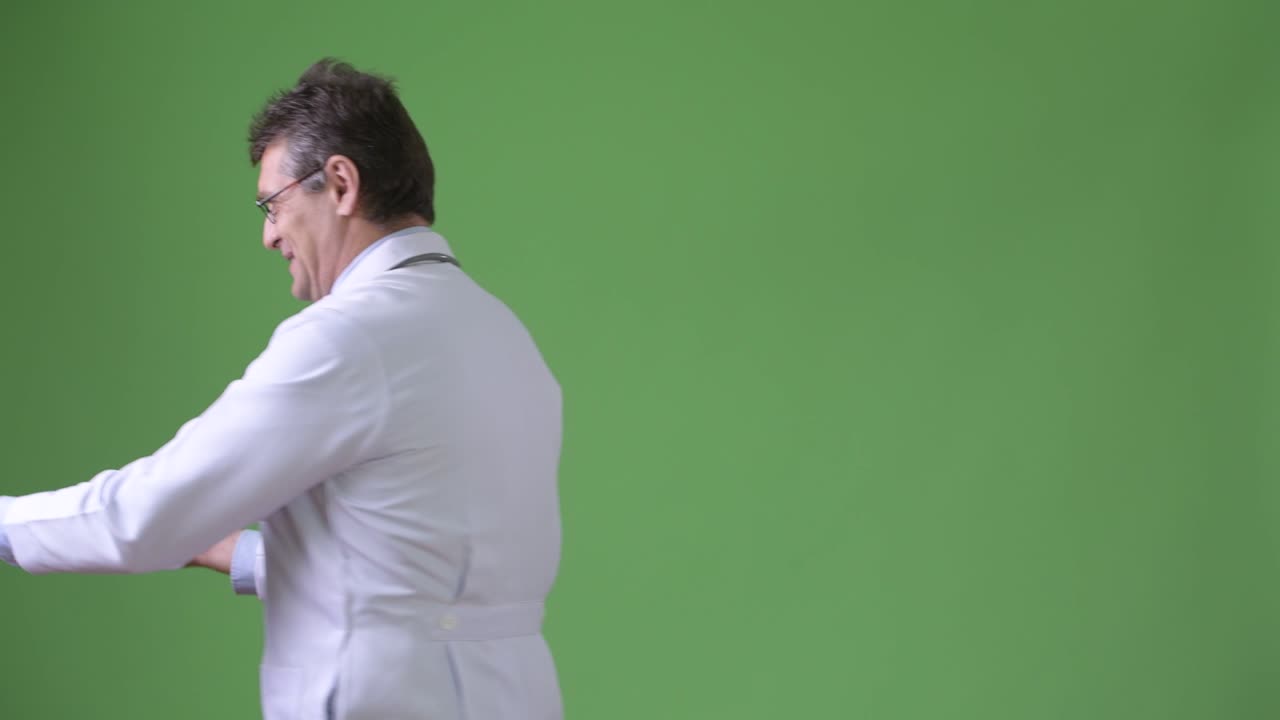 Médico maduro e bonito contra fundo verde.