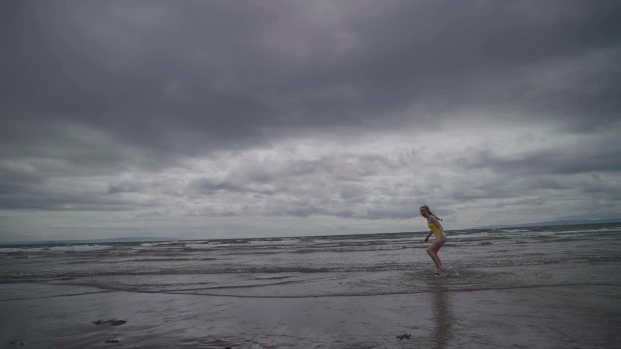 Adolescente ripreso al rallentatore mentre corre verso il mare e si volta indietro.