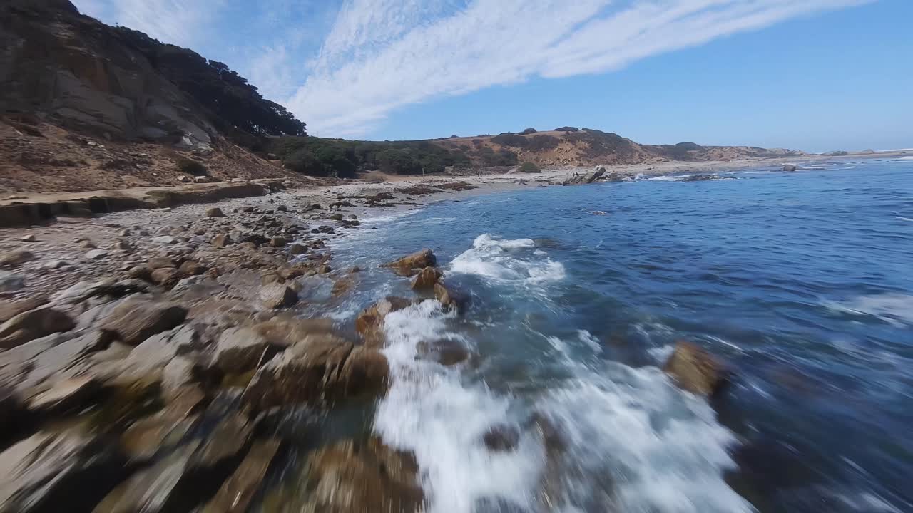 Drone FPV cinematografico che vola vicino alla costa del mare cileno con acqua turchese e paesaggio roccioso, di giorno.