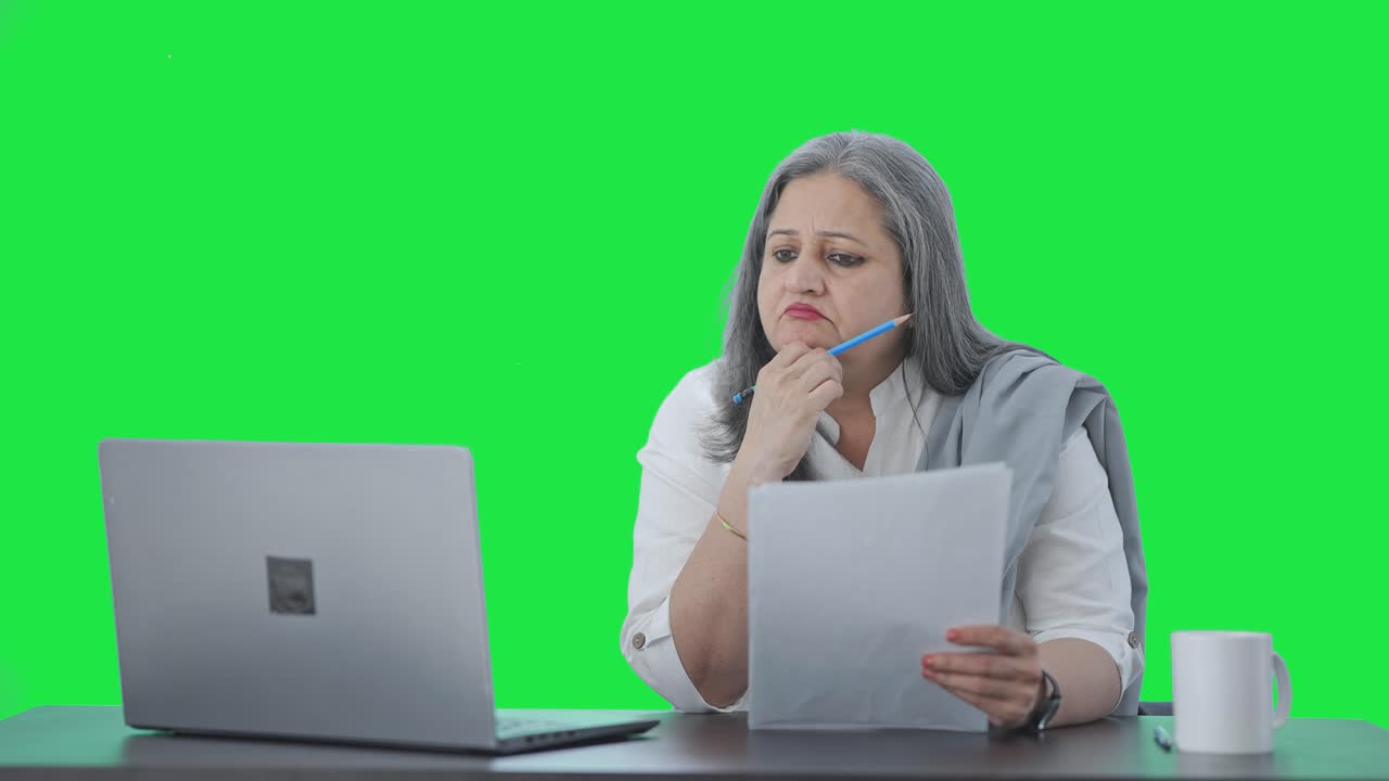 confundida directora india senior leyendo informes de negocios pantalla verde