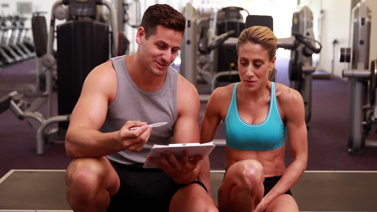건강 한 여자 와 트레이너 가 그 의 진보 에 대해 이야기 하고 있다