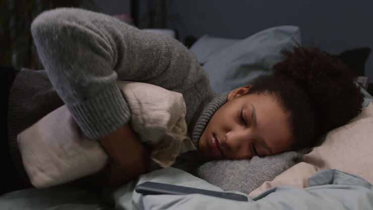 Mujer joven abrazando una almohada y recostada en el dormitorio.