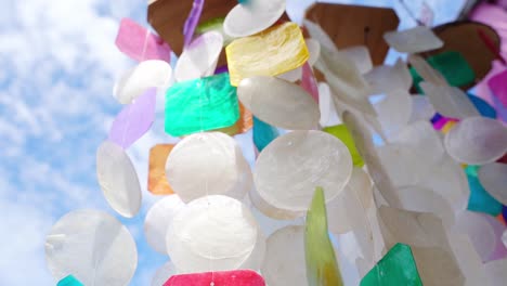 colorful shell wind chimes against a cloudy sky