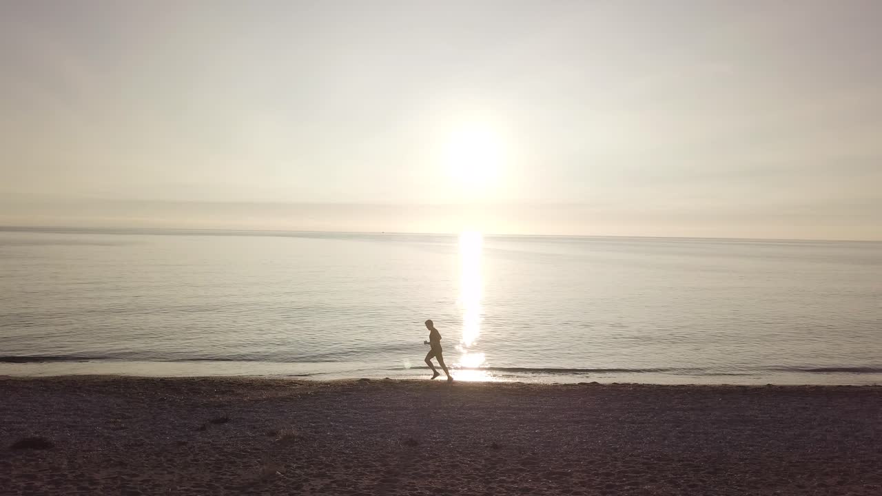 Young athlete runner man with fit strong body training on beautiful sunset at beach