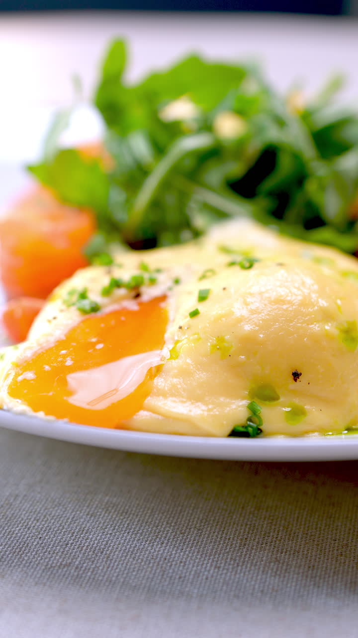 Traditional Ukrainian banosh corn porridge featuring poached salmon, soft running egg yolk, fresh arugula, and chopped chives served on white plate, highlighting gourmet culinary presentation