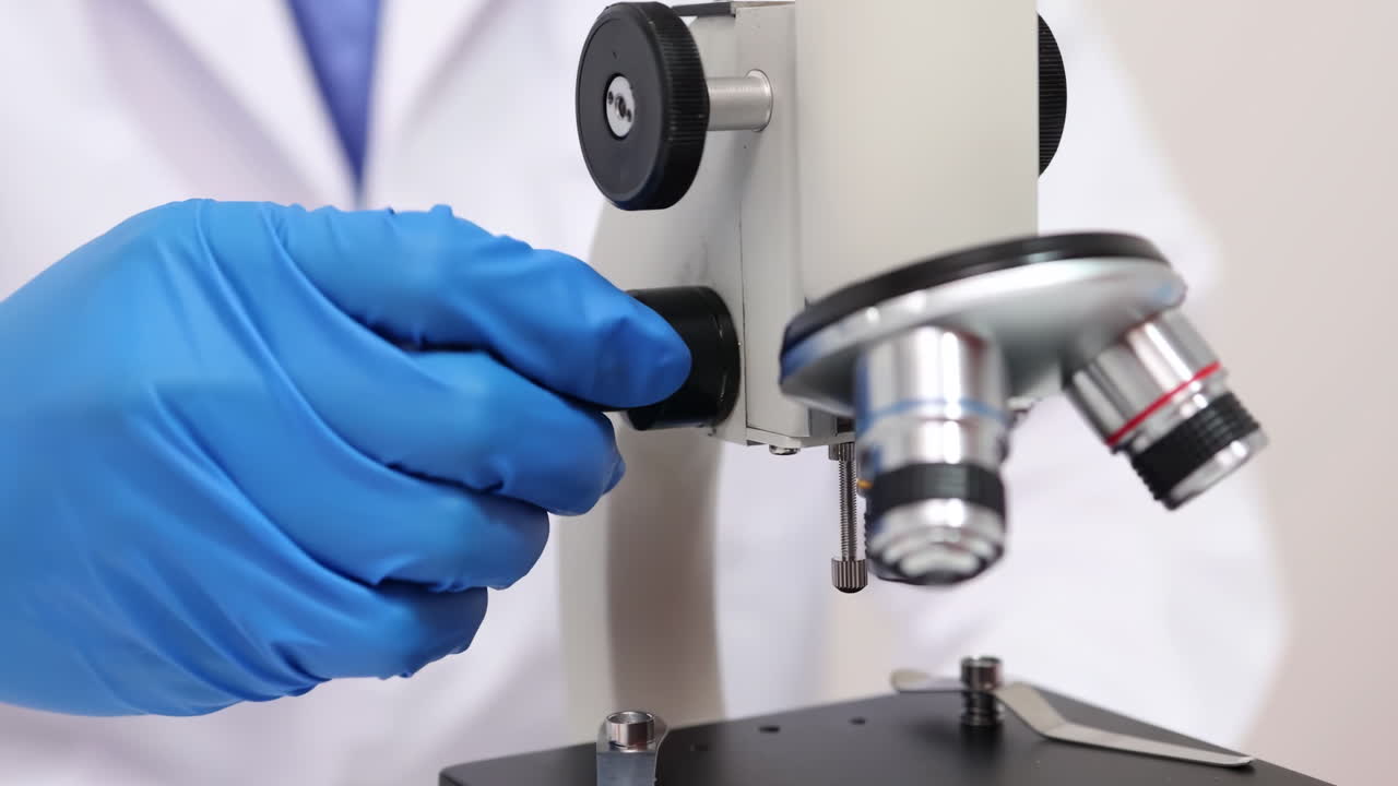 A scientist works tirelessly in a lab examines samples through a microscope, highlighting advances in gene therapy and its applications