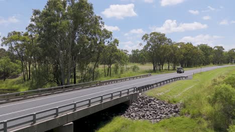 vehicle crossing bridge in lush australian landscape