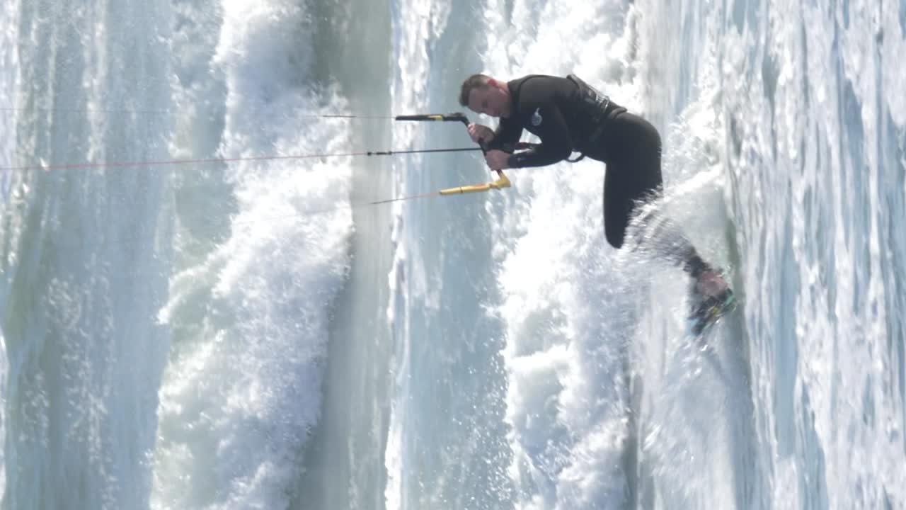 Kitesurfer riding waves off Cape Town’s Big Bay with powerful surf and bright, clear skies, vertical shot