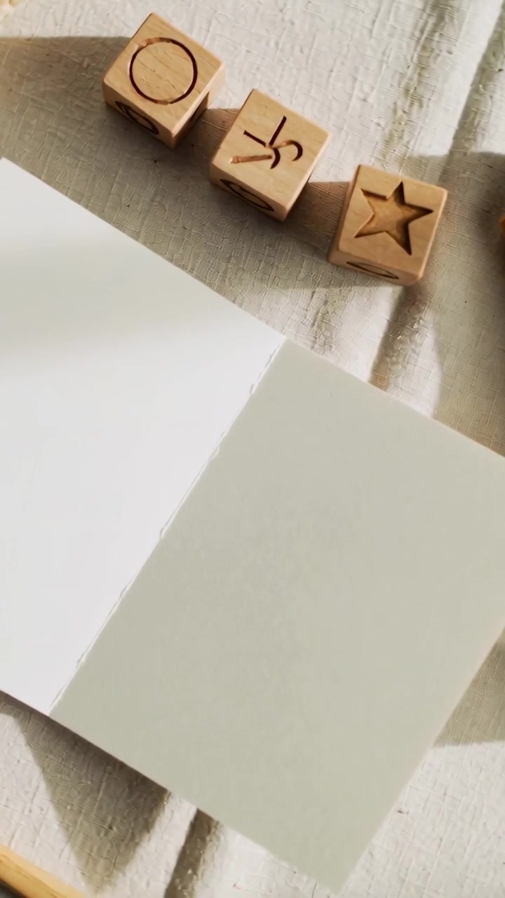 Video verticale: Telecamera che si inclina e inquadra una carta aperta su un tavolo, incorniciando la carta con blocchi su un panno color senape.