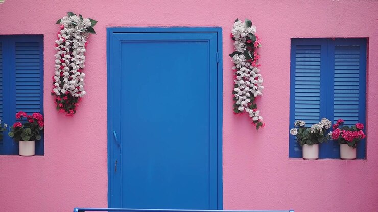 Parede rosa vibrante com porta e venezianas azuis