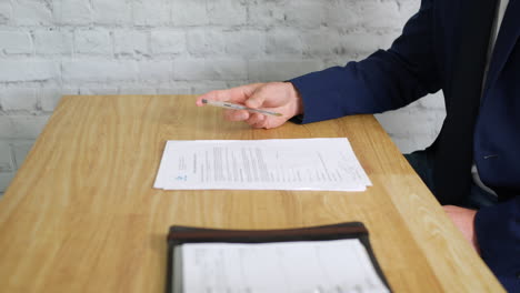 un hombre de negocios aburrido que espera una reunión hace girar su pluma mientras está inquieto en su escritorio