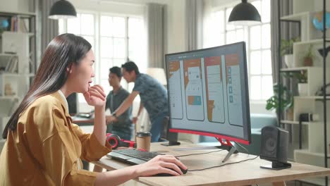 tired asian female mobile application developer works with graphics on her personal computer in office