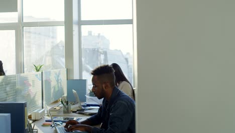 african american office worker texting on laptop