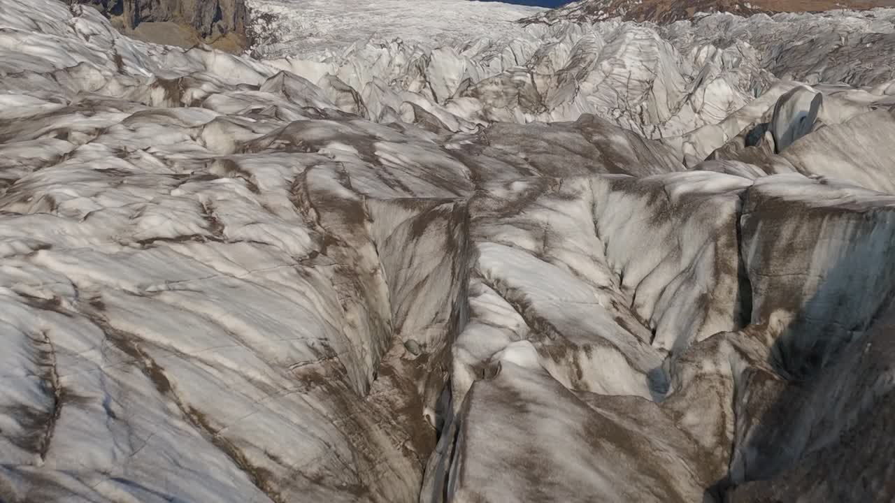 Rekaman udara ladang gletser Islandia yang luas, menampilkan celah dalam dan formasi es yang tertutup salju. Pemandangan menakjubkan dari medan glasial murni dan hutan belantara beku yang terjal