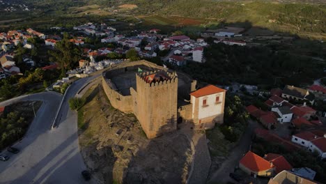 a drone pulls back from the tower at belmont castle at sunset surrounded by birds