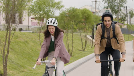 Front-View-Of-American-Man-And-Woman-Riding-Bikes-And-Talking-To-Each-Other-While-Going-To-Work