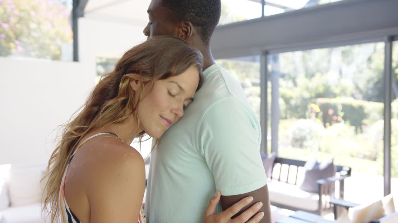 Diverse couple embracing, Caucasian woman resting head on partner, at home