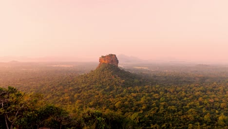 a woman calmly walks across the summit of pidurangala rock, making her way to witness the breathtaking sunrise over sigiriya rock.
