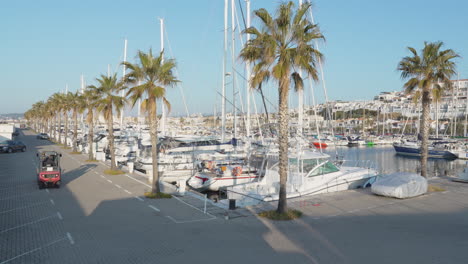 forklift drives on a road past yachts docked at port during sunny morning