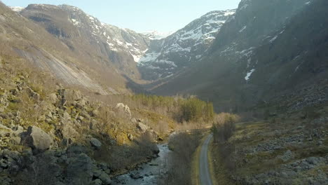 drone shot of a river in norway tilting up to reveal beautiful snow capped mountains, forward flying motion