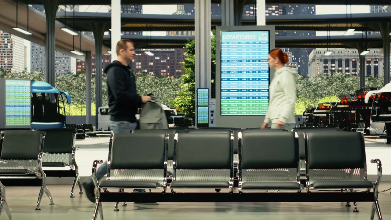 Monipuolinen ryhmä matkustajia ohittamassa linja-autoasemaa käsimatkatavaroiden kanssa.