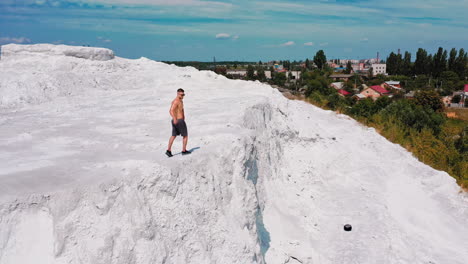 brutal strong bodybuilder posing outdoor. photoshoot in a quarry. outdoor sports concept. aerial view. posing and pumping muscles. white landscape.