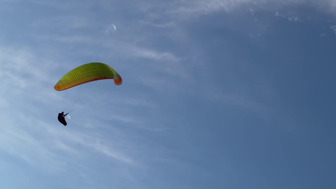 un piloto de parapente se eleva con gracia contra el telón de fondo del cielo azul, encarnando la libertad de vuelo en medio de horizontes sin límites