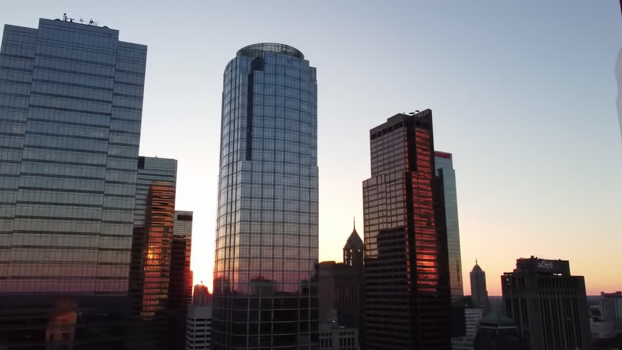 The vibrant sunset paints the skyline in shades of orange and pink, while sleek skyscrapers reflect the colors of dusk in a bustling urban environment.