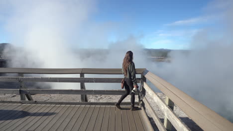 female photographer walking on lookout above steam in yellowstone national park, wyoming usa, full frame